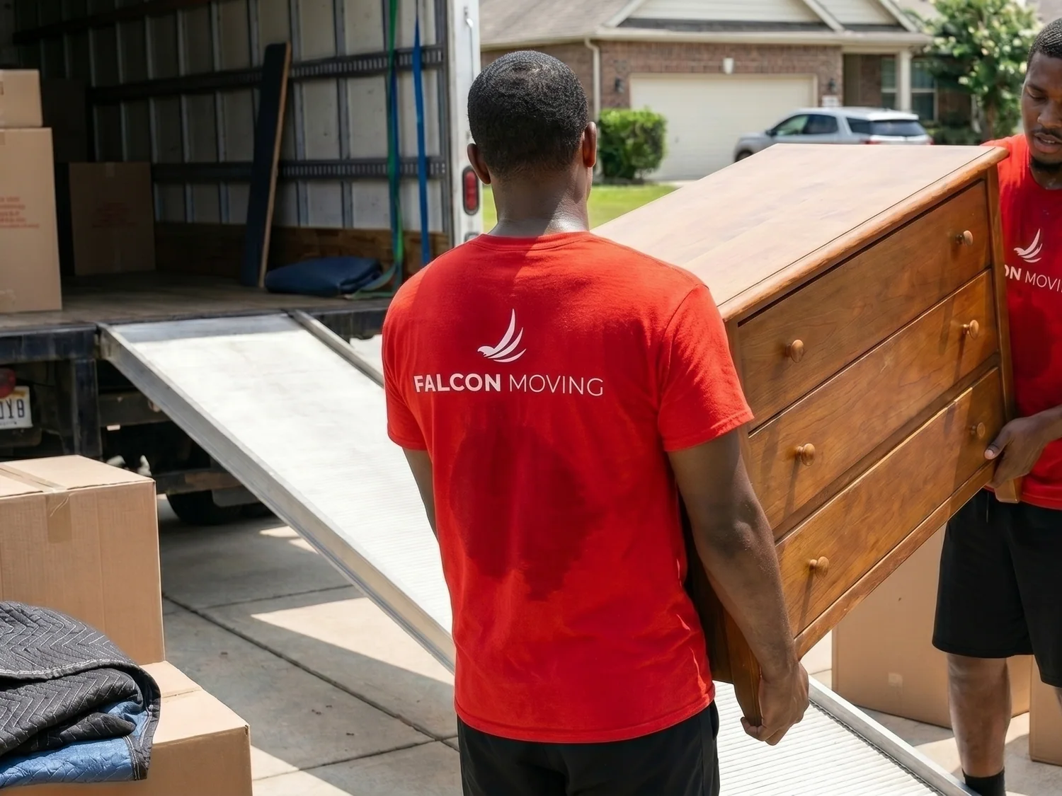 Falcon Moving team carrying furniture toward a moving truck
